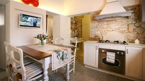 Een moderne keuken met een stenen muur, witte kasten en een rood decoratief element aan het plafond.