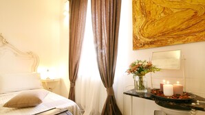 Een slaapkamer met een bed, gordijnen, een vaas met bloemen en een nachtkastje.