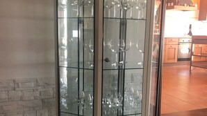 Ett hörnskåp med flera hyllor där det förvaras genomskinligt glas.