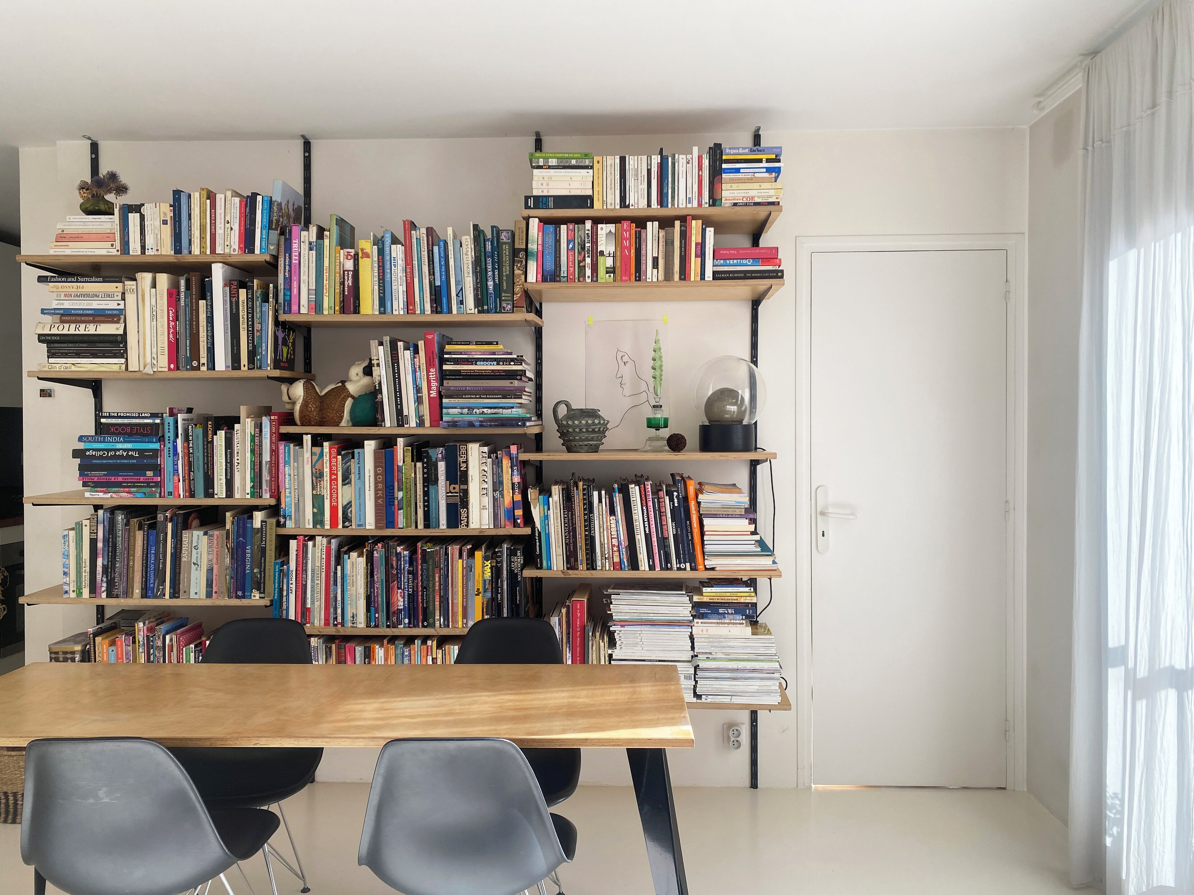 Une pièce comprenant une grande bibliothèque en bois remplie de livres, une table en bois et deux chaises.