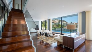 Un intérieur moderne avec un escalier en bois, un coin salon offrant une vue sur la ville et une grande fenêtre donnant sur le paysage.