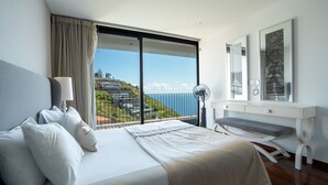 Une chambre d’hôtel moderne avec un grand lit, un bureau et une vue sur l’océan.