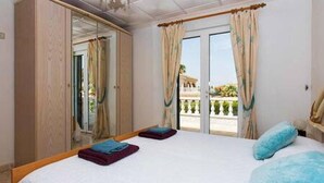 Een slaapkamer met een groot bed, een kledingkast en een balkon met uitzicht.