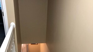 A carpeted staircase with white balusters and a handrail, leading to a landing with a door.