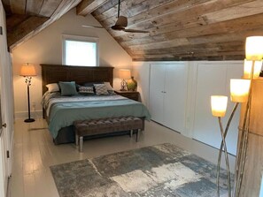 Cozy retreat with a loft-style design, featuring a large bed, bedside tables, and a comfortable bench.