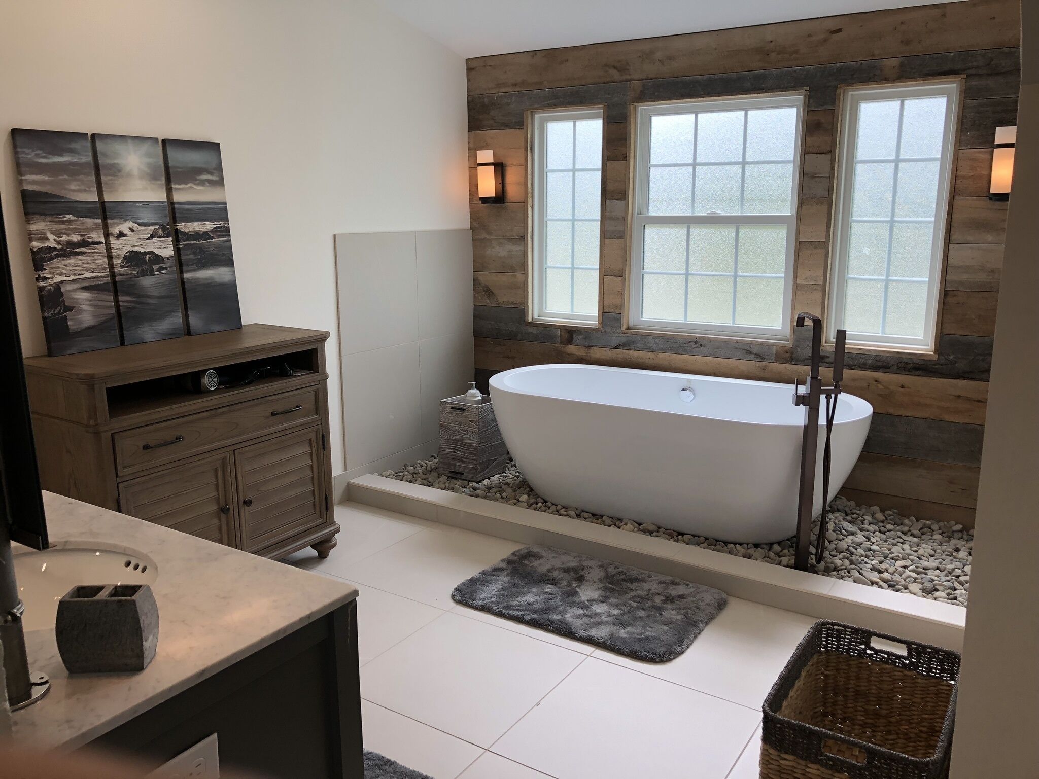 Une salle de bain moderne avec une baignoire sur pieds, un lambris en bois et une grande fenêtre.