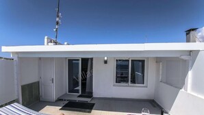 Un petit bâtiment blanc, de plain-pied, doté d’une porte coulissante en verre, d’une petite fenêtre et d’une antenne métallique sur le toit.