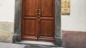 A wooden double door with a metal decorative top, a small plaque, and a 'next sale' sign on a building facade. - Garibaldi Suite - Turin's downtown - Turin center (Torino)