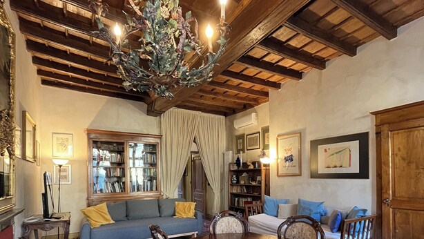 A dining area with a wooden table and chairs, surrounded by a patterned rug, with a chandelier above. - Garibaldi Suite - Turin's downtown - Turin center (Torino)