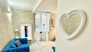 Una stanza con un divano blu, una decorazione a forma di cuore e un muro in pietra.