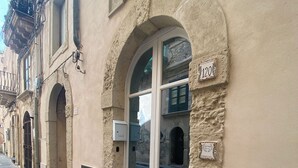 Un edificio con facciata in pietra, numero 120, con un'ampia finestra ad arco e un ingresso.