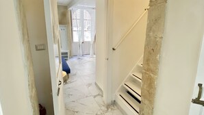 Un corridoio con pavimento in marmo, una porta bianca e una scala che conduce a un'altra stanza.