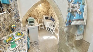 Una cucina angusta con un arco in pietra, una lavatrice, un forno a microonde e un piccolo tavolo con sedie.