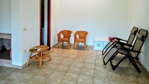 Une pièce comprenant deux fauteuils en osier, une petite table, un canapé et un buffet.