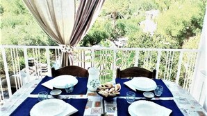 Une table de balcon dressée avec des assiettes, des verres et un centre de table décoratif.