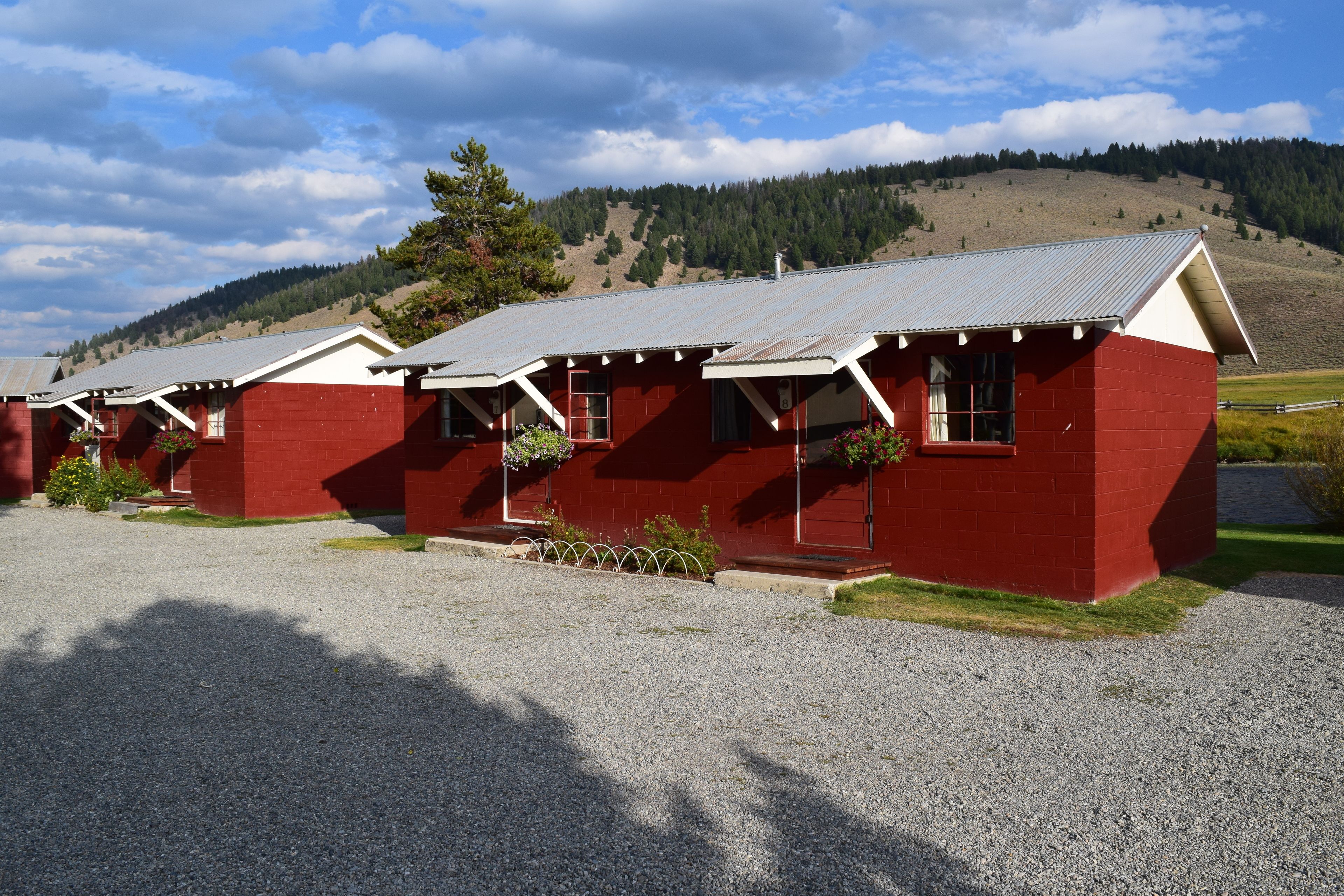 Une rangée de cabanes rouges aux toits métalliques, se détachant sur un paysage vallonné.