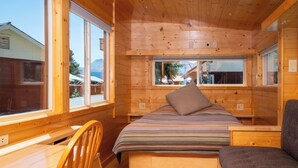 Una cabaña de madera con una cama, un escritorio y una silla.