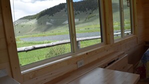 Una habitación con amplios ventanales que ofrecen vistas a un río y colinas.