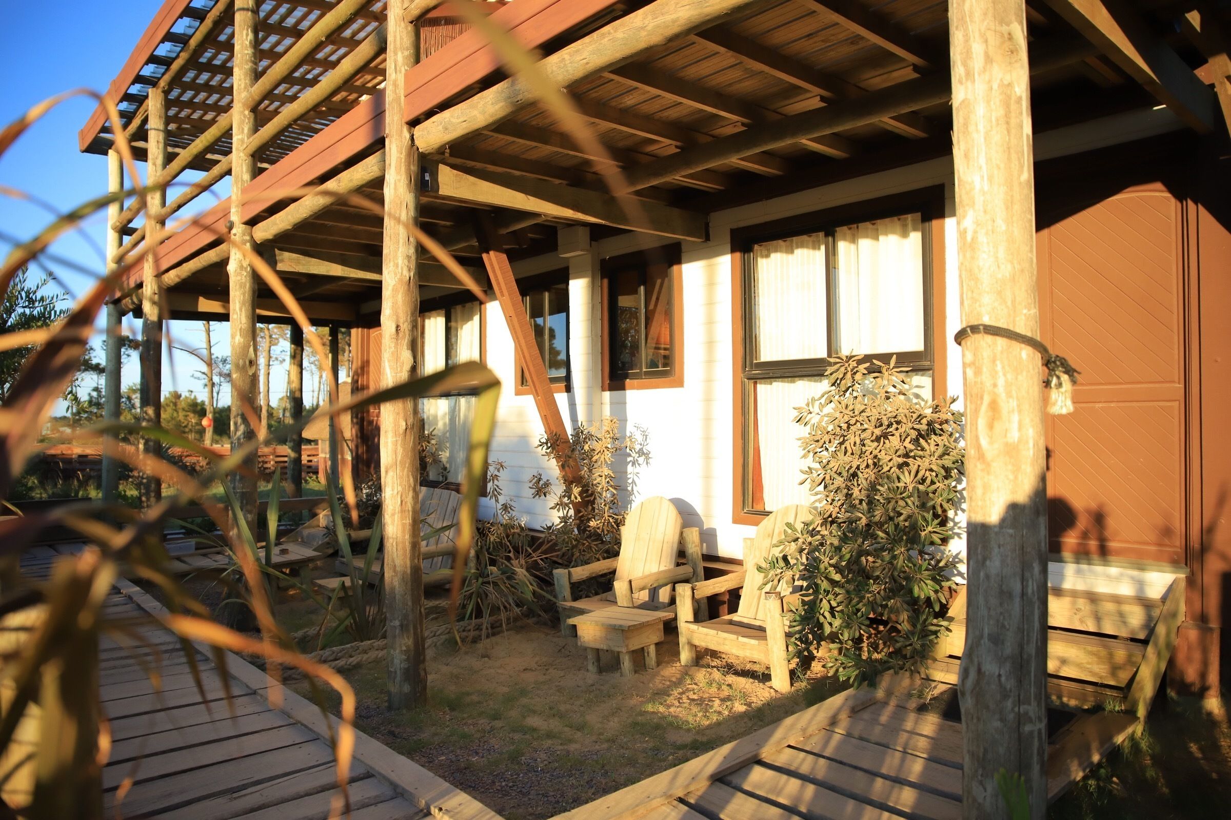 A rustic wooden structure with a covered porch, outdoor seating, and a small garden area.