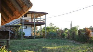 A two-story house with a wooden deck and a brick wall. - mandalas demar (Punta del Diablo)
