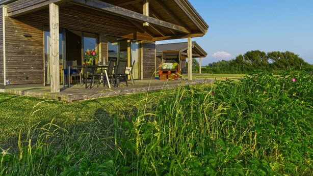 A wooden house with a covered porch, a dining table, and chairs. - (25) Gud Jard Lodge Seestern, Cat. TraumBlick - Design vacation home Seestern (25) (Pellworm)