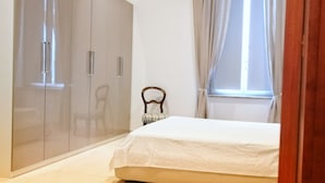 A bedroom with a bed, a wardrobe, a chair, and a window with curtains. - Da Bianca Apartment in Siena (Siena)