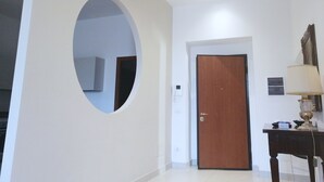 A hallway with a wooden door, a small table with a lamp, and a wall-mounted air conditioning unit. - Da Bianca Apartment in Siena (Siena)