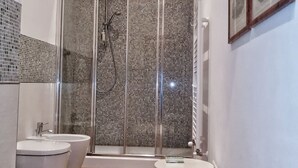 A bathroom with two sinks, a shower with a glass door, and a small stool. - Da Bianca Apartment in Siena (Siena)