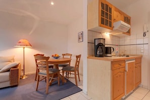 A compact living space with a dining area, kitchenette, and a lamp.