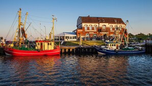 Two boats docked at a pier with a building in the background.