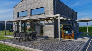 A modern house with a wooden deck, a covered patio, and a barbecue area.