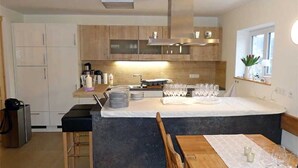 Een moderne keuken met een centraal eiland, houten kastjes en een eethoek met een tafel en stoelen.