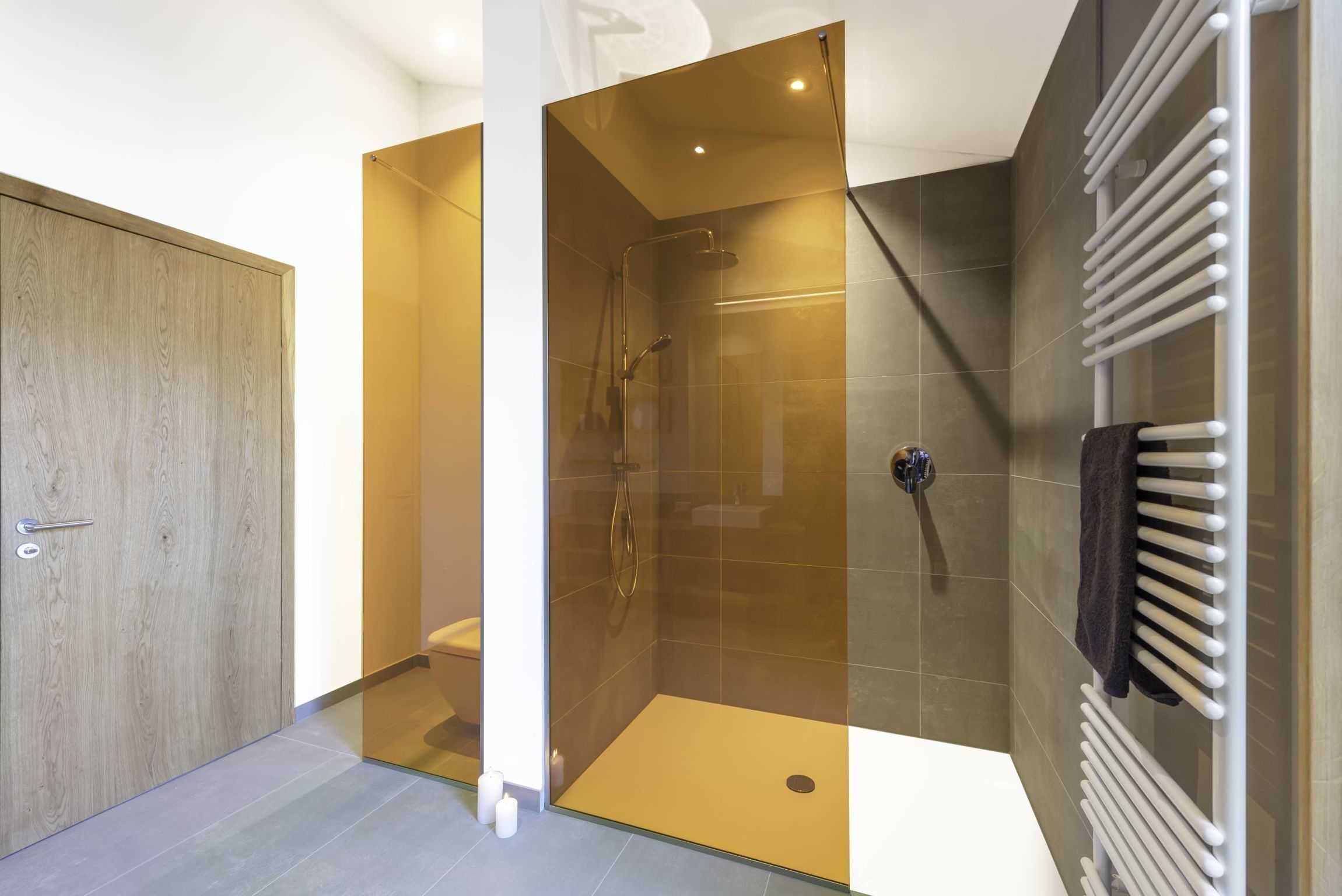 A modern bathroom with a glass-enclosed shower, a white bathtub, and a wooden door.