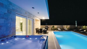 A swimming pool with a hot tub, outdoor seating, and a patio area at night. - Beautiful home in Sukosan (Sukosan)