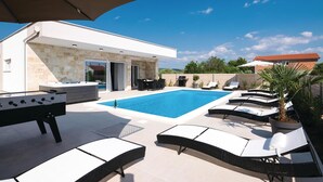 A modern outdoor pool area with lounge chairs, a hot tub, and a barbecue grill. - Beautiful home in Sukosan (Sukosan)