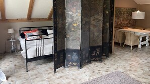 Ein Zimmer mit einem Bett, einem Tisch mit Stühlen, einem Zierbildschirm und einer Lampe.