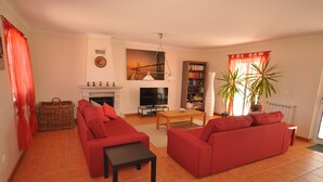 Ein Wohnzimmer mit roten Sofas, einem Kamin, einem Fernseher und einem Bücherregal.