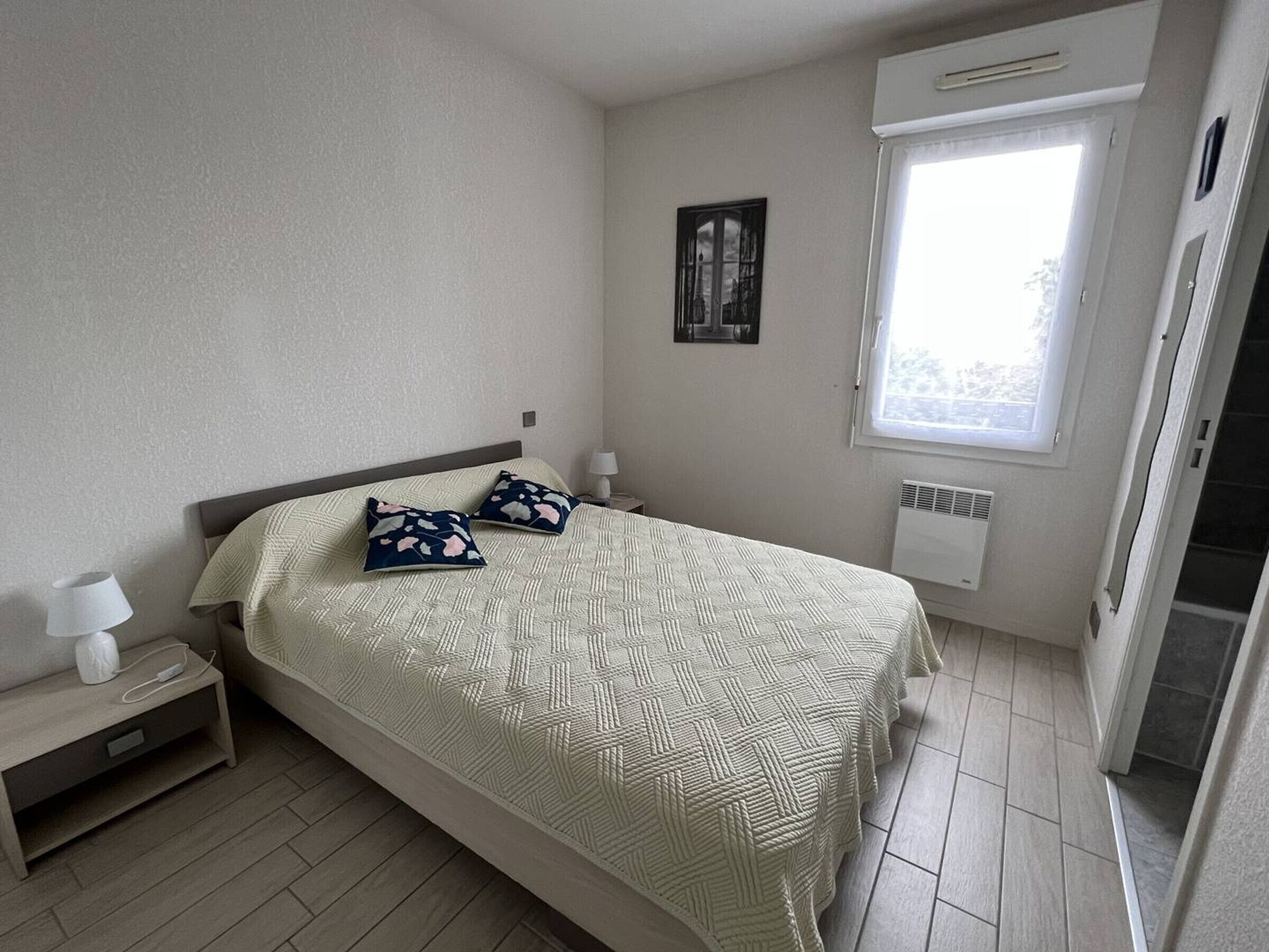 A bedroom with a bed, nightstands, a window, and a radiator.