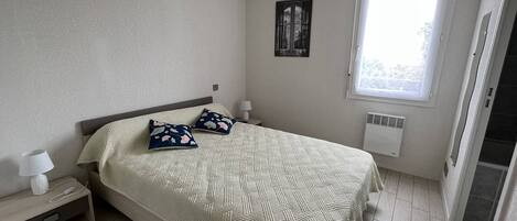 A bedroom with a bed, nightstands, a window, and a radiator.