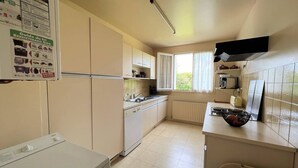 Eine kleine Küche mit weißen Schränken, einem eingebauten Backofen, einem Fenster mit Vorhängen und einer gefliesten Spritzschutzwand.