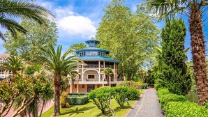 Ein Gebäude im traditionellen Stil mit blauem Dach, umgeben von üppiger Vegetation und Palmen.