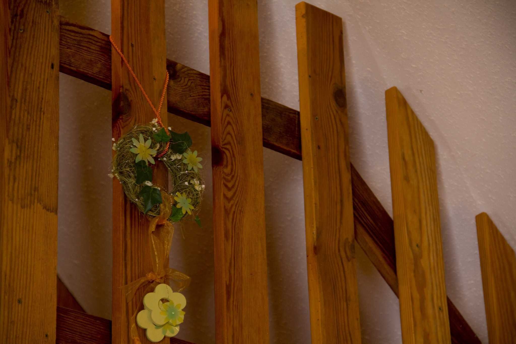 A wooden staircase with a decorative wreath hanging on the side.