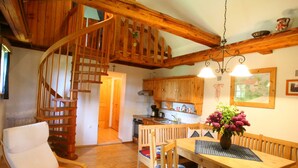Un interior de madera con una escalera en espiral, un comedor con mesa y sillas, y armarios de madera.