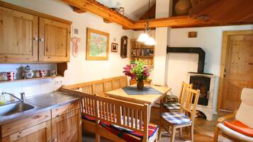 Une cuisine rustique avec des meubles en bois, une table à manger avec des bancs, une cheminée et une bibliothèque.