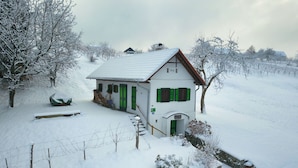 Una casa cubierta de nieve con techo inclinado, contraventanas verdes y el año '1952' visible en la fachada.