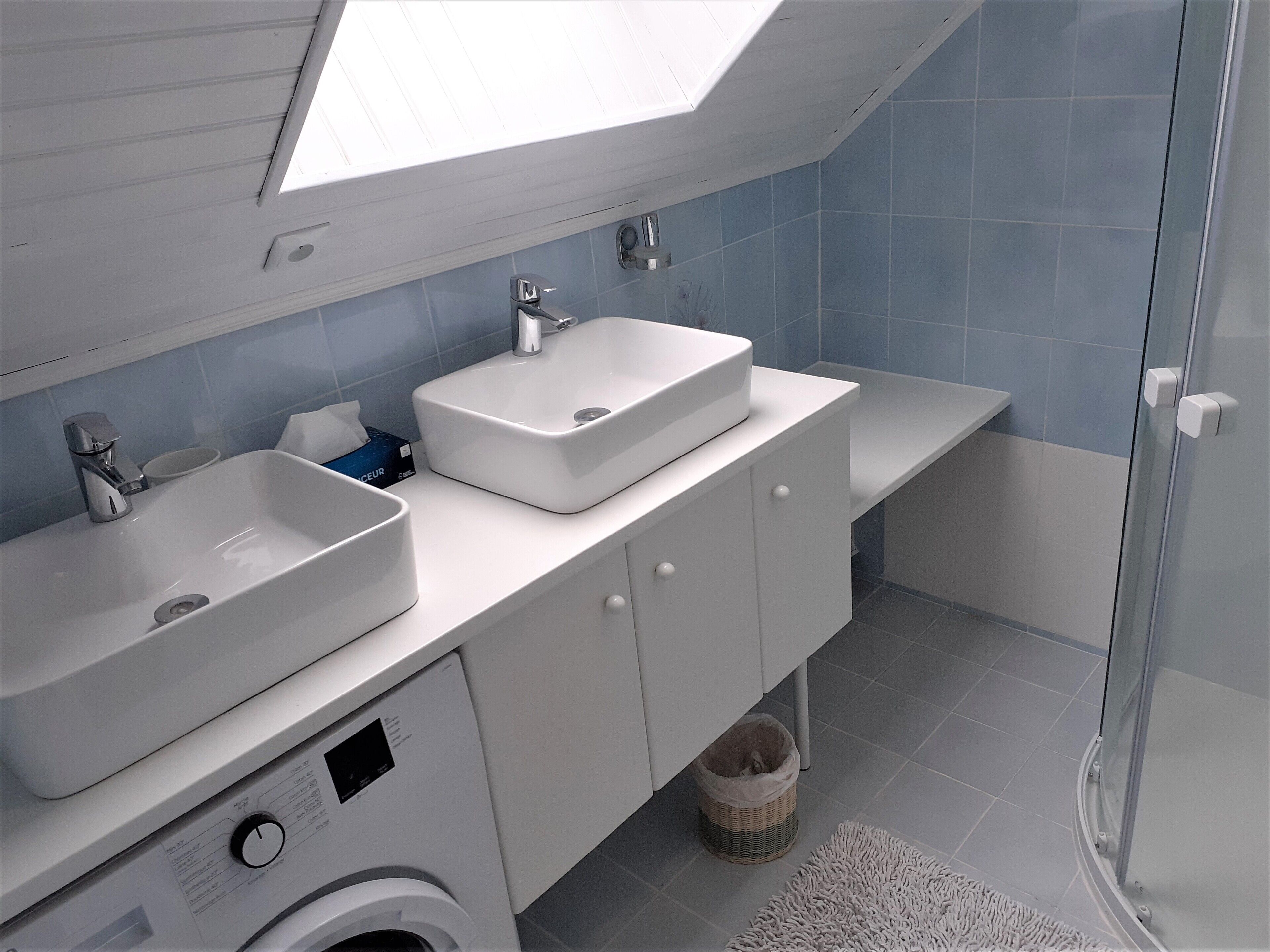 Un bagno moderno con due lavandini, una lavatrice e un box doccia in vetro.
