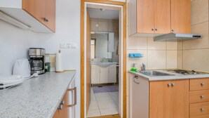 Una cocina compacta con armarios de madera, un lavamanos de acero inoxidable y una cafetera.