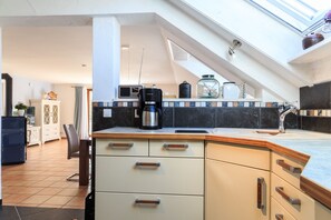A kitchen with a coffee maker, a microwave, and a glass jar on the counter.