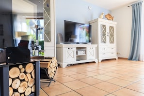 Ein Wohnzimmer mit Fernseher, weißen Schränken und einem Kamin.