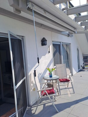 A balcony with a table, chairs, and a window. - Apartment Sonnenschein with Terrace (Hergatz)